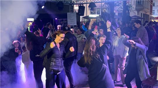 Ausgelassen tanzen die Gäste der Open-Air-Disco am Geesttor zu elektronischen Beats. Die Tanzfläche ist in Bühnennebel gehüllt.