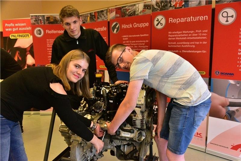 Auszubildender Jannes Kettler von der Firma Hinck schraubt mit den Schülern Olga Wolf und Finn-Niklas Müller an einem Motor. Foto: Beneke