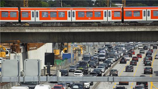 Autos stehen auf der A7 an der Anschlussstelle Othmarschen vor dem Elbtunnel Richtung Süden in einem Verkehrsstau. Über der Autobahn verläuft ein Bahntrasse, über die ein Hamburger S-Bahn-Zug rollt.
