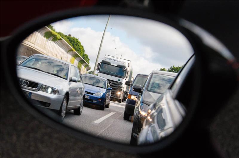Autos und Lastwagen stehen im Stau und sind dabei durch einen Rückspiegel zu sehen. Foto: Daniel Bockwoldt/dpa