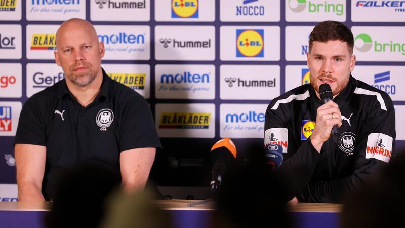 Axel Kromer (l) und Kapitän Johannes Golla sitzen während einer Pressekonferenz auf dem Podium.