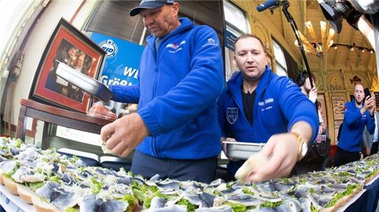 Axel Schulz, ehemalige Profiboxer (l-r), und André Domke Fischsommelier und Fischhändler belegen das gigantische Fischbrötchen mit Salat, Fisch und Zwiebeln.