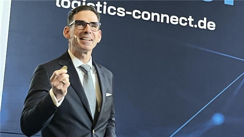 BLG-Chef Matthias Magnor hält auf der Messe Logistics-Connect eine 50-Cent-Münze hoch, um zu verdeutlichen, wie wenig Geld der Bund jährlich den deutschen Häfen zur Verfügung stellt.