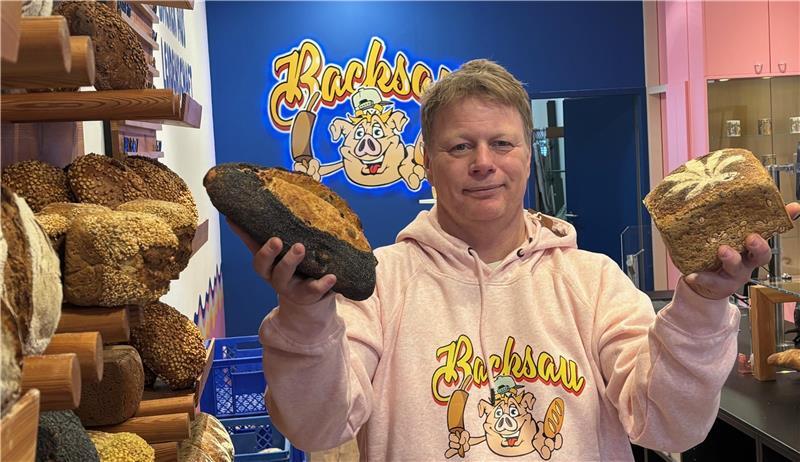 Backsau-Inhaber Sascha Schäfer steht in seiner Filiale an der Straße Zwischen den Brücken in Buxtehude. Auf dem Foto zeigt der Bäckermeister ein Dinkel-Cashew-Cranberry-Brot (links) und sein Hanfbrot.
