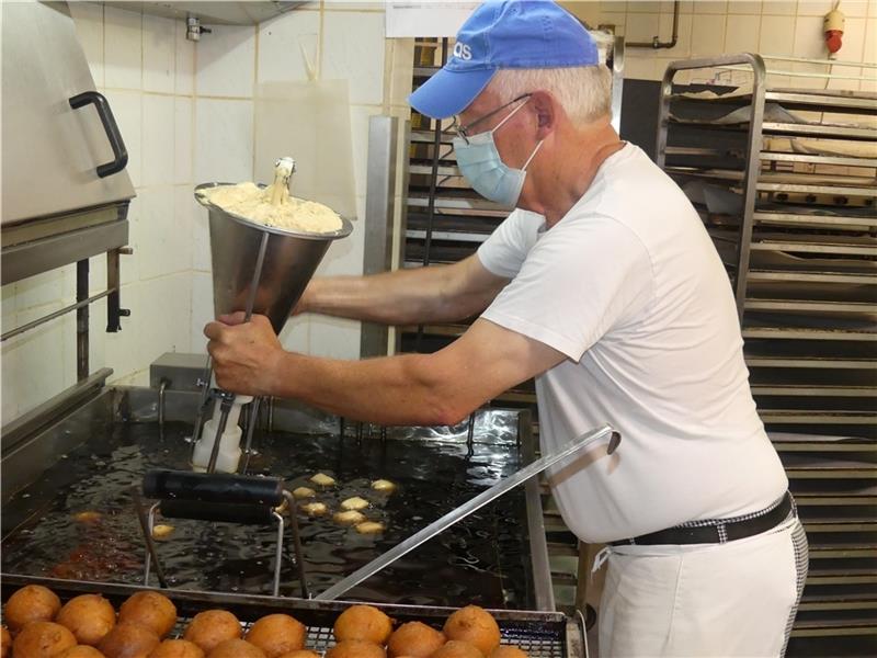 Bäcker Norbert Wiechers (71) presst den Teig für die Quarkbällchen ins heiße Öl. Mit der manuellen Presse – die neue automatische funktioniert noch nicht so, wie sie soll. Fotos: Knappe