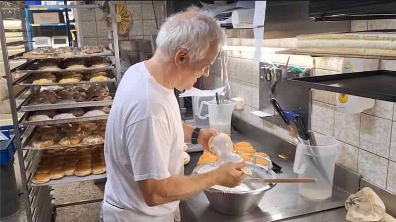 Morgens um 2 Uhr beginnt ihr Tag: Einblick in eine Traditionsbäckerei Bäckermeister Rolf Schwarz glasiert die frisch gebackenen Berliner. Mit seinem Team backt er über 100 verschiedene Produkte am Tag für hungrige Kunden.