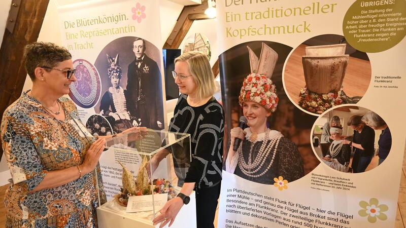 Barbara Wetegrove (links) und Dr. Kai Janofsky rücken die Vitrine mit dem ersten Flunkkranz der Altländer Blütenköniginnen ins rechte Licht.