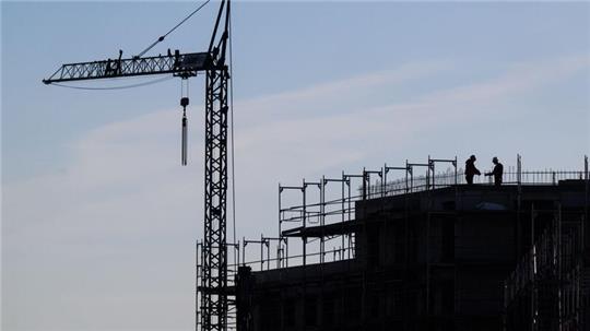 Bauarbeiter stehen auf der Baustelle eines Mehrfamilienhauses.