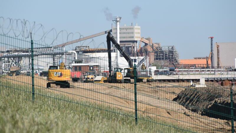 Baustelle hinter einem Sicherheitszaun und Kameraüberwachung: Auf rund 1200 Metern wird am LNG-Terminal in Stade ein neuer Deich angelegt.