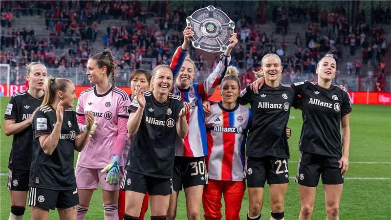 Bayerns Spielerinnen jubeln nach Spielende gegen den 1. FC Union Berlin mit der Nachbildung einer Meisterschale über den Sieg.