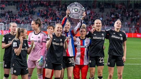 Bayerns Spielerinnen jubeln nach Spielende gegen den 1. FC Union Berlin mit der Nachbildung einer Meisterschale über den Sieg.