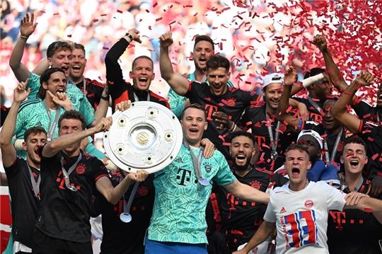 Bayerns Torhüter Manuel Neuer (Mitte) hält die Meisterschale während seine Teamkollegen nach dem Gewinn der 33. deutschen Meisterschaft jubeln. Foto: Federico Gambarini/dpa