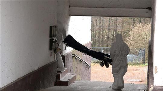 Beamte der Spurensicherung bringen eine Trage in ein Wohnhaus. 