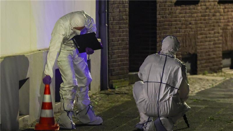 Beamte der Spurensicherung in Spurensicherungsanzügen begutachten den Tatort.