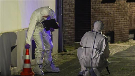 Beamte der Spurensicherung in Spurensicherungsanzügen begutachten den Tatort.