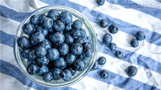 Beeren statt Chips oder Nüsschen: Heidelbeeren, auch Blaubeeren genannt, liegen auf einem Esstisch und werden gern gesnackt.