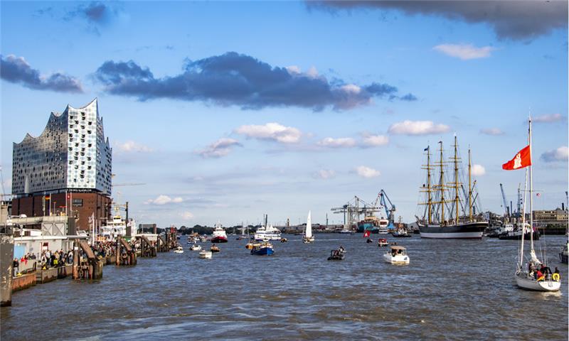 Begleitet von dutzenden Schiffen wird die Viermastbark «Peking» (rechts im Hintergrund) in den Hamburger Hafen geschleppt. Foto: Axel Heimken/dpa