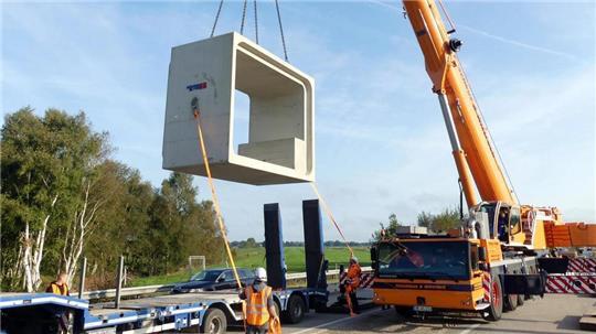Bei Nordholz wird derzeit der Durchlass für den Altenbrucher Kanal erneuert. Dabei werden Betonteile durch die teilweise geöffnete Fahrbahn eingepasst.