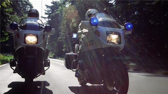 Zwei Polizisten fahren mit einem Krad.