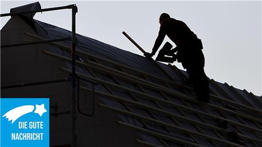 Ein Dachdecker arbeitet auf einem Hausdach.