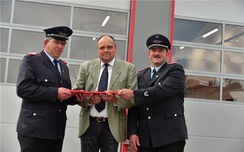 Bei der Schlüsselübergabe vor dem neuen Feuerwehrhaus (von links): Ortsbrandmeister Holger Kuck, Samtgemeindebürgermeister Michael Gosch und Gemeindebrandmeister Jens Kuck. Foto Beneke