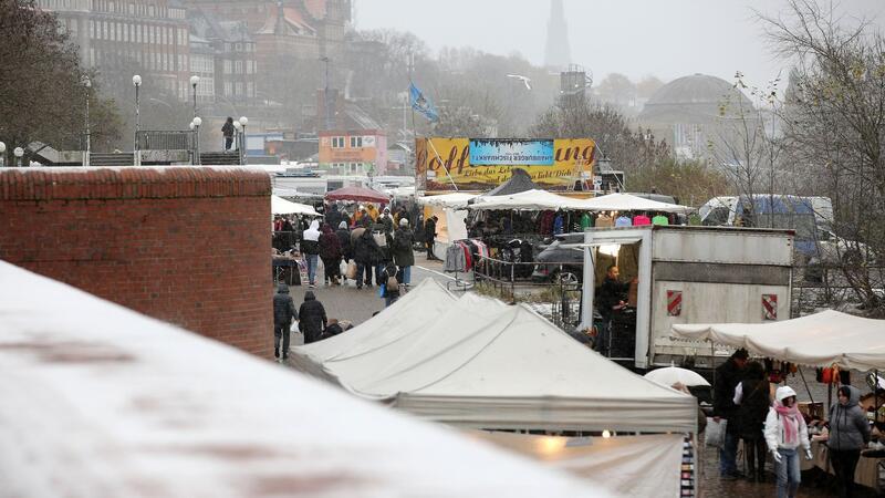 Bei leichtem Schneefall sind Besucher auf dem Hamburger Fischmarkt unterwegs.