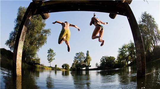 Beim Baden ist Vorsicht wichtig - hier springen zwei Menschen in einen See in Hannover. (Symbolbild)