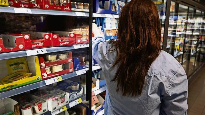 Eine Frau greift in ein Supermarkt-Regal.