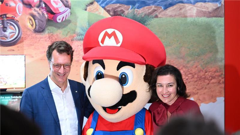 Beim Messerundgang über die Gamescom kam der Tross von Politikern auch beim Messestand von Nintendo vorbei, hier stehen NRW-Ministerpräsident Hendrik Wüst (CDU) und Bundesforschungsministerin Dorothee Bär (CSU) neben einer Mario-Plüschfigur.