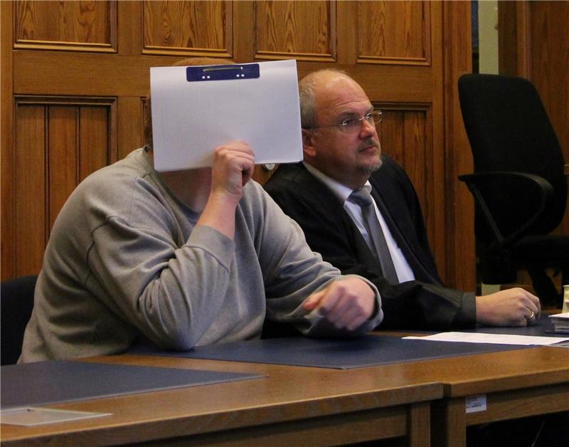 Beim Prozessauftakt im Stader Landgericht verdeckt der Angeklagte sein Gesicht mit einer Akte. Rechts neben ihm nimmt sein Verteidiger, der Cuxhavener Rechtsanwalt Andreas Meyn, Platz. Foto Mangels