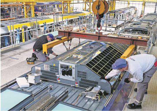 Beim Zughersteller Alstom in Salzgitter hievt in der Produktionshalle ein Kran eine Brennstoffzelle aufs Dach eines Wasserstoffzuges. Die Produktion der 14 Triebfahrzeuge für das Weser-Elbe-Netz der EVB läuft auf Hochtouren. Foto: Busse/Alstom