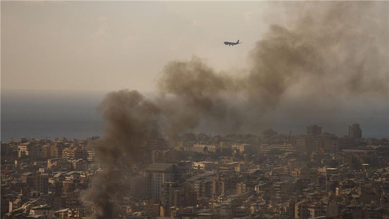 Beirut, Libanon: Verkehrsflugzeug im Landeanflug, während Rauch nach israelischen Luftangriffen aus südlichem Vorort aufsteigt