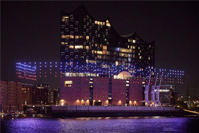 Beleuchtete Drohnen fliegen über der Elbe vor der Elbphilharmonie.