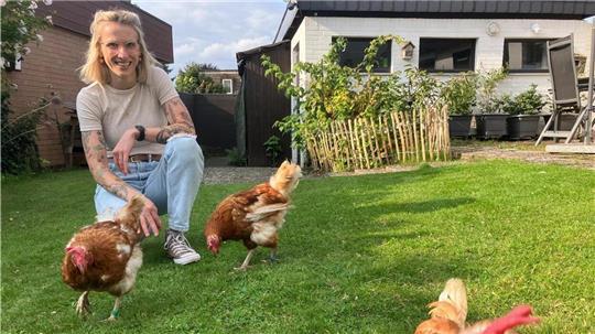 Hühner-Retterin Kristina Harder sitzt mit drei Hühnern in ihrem Garten in Visselhövede. 