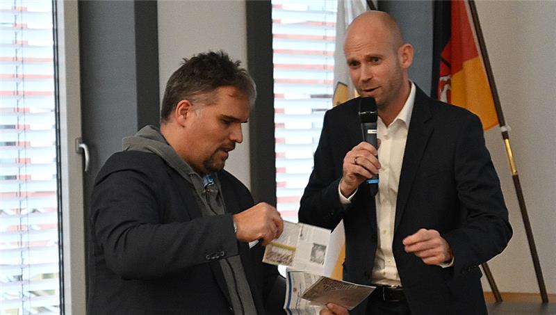 Benjamin Koch-Böhnke (Die Linke) übergibt Sebastian Rauba (rechts) vom Polizeilichen Staatsschutz zwei Postkarten mit Hassbotschaften. Foto: Vasel