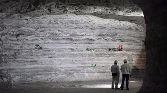 Bergleute betrachten die Salzschichten mit Markierungen für Bohrungen.Fotograf