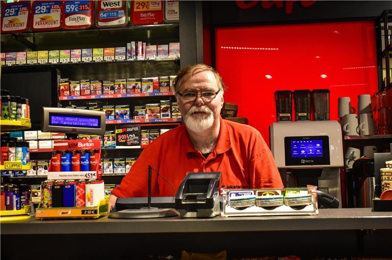 43 Jahre, „Schießereien“ und ein Mercedes: Bernd ist in Hedendorf Kult Bernd steht hinter der Kasse. Im Hintergrund sind Zigaretten in einem Regal.