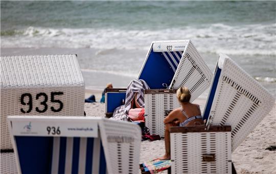 Besucher des Strands genießen die Sonne in Strandkörben. Noch sind die Strände auf den nord- und ostfriesischen Nordseeinseln leer - doch vielerorts können schon jetzt Strandkörbe für den Sommer gebucht werden. Foto: Axel Heimken/dpa