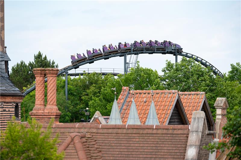 Besucher fahren mit einem Fahrgeschäft über Bäumen und Dächern des Hansa-Parks.  Foto: Jonas Walzberg/dpa