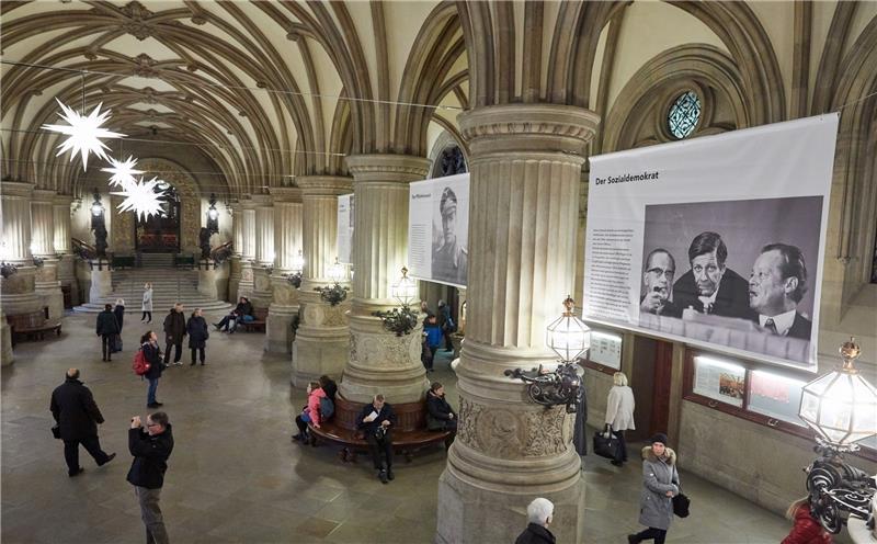 Besucher gehen durch die Rathausdiele des Hamburger Rathauses unter Bannern aus der Fotoausstellung „100 Jahre in 100 Bildern“ zum 100. Geburtstag Helmut Schmidts. Fotos Wendt/dpa