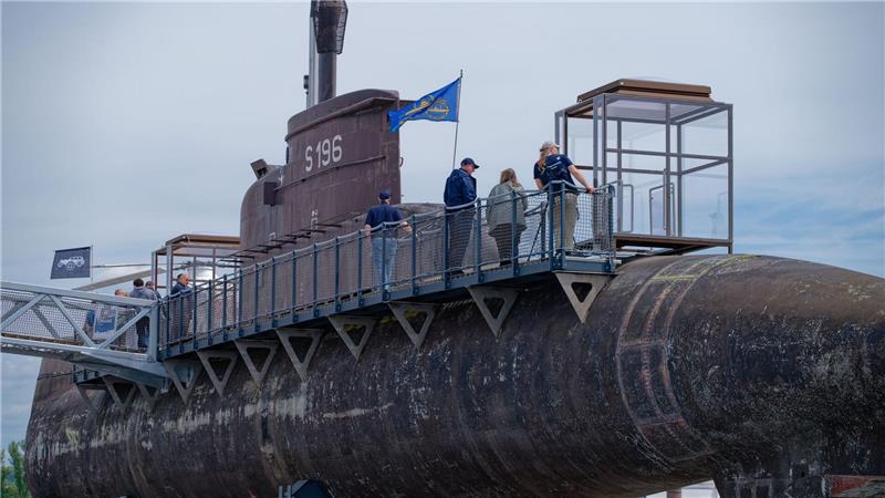 Besucher gehen über einen Steg am Marine U-Boot U17 entlang. 
