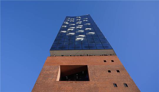 Besucher genießen den Ausblick von der Elbphilharmonie-Plaza auf den Hafen. Die Elbphilharmonie-Plaza ist ein beliebter Aussichtspunkt für Touristen und Einheimische. Bisher war der Besuch kostenlos. Das soll nach Aussagen des Kultursenators auch weiterhin so bleiben. Foto: Marcus Brandt/dpa