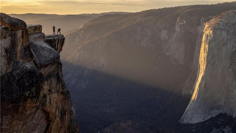 Besucher posieren für ein Foto auf einem Felsvorsprung in der Nähe von Taft Point im Yosemite Nationalpark in den USA.