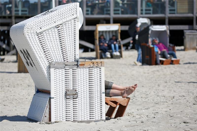 Touristiker freuen sich über gute Buchungsnachfrage an Pfingsten Besucher sitzen bei Sonnenschein und Temperaturen um 14 Grad Celsius in Strandkörben am Strand von St. Peter-Ording. Die Touristikerinnen und Touristiker in Schleswig-Holstein sind mit der Buchungsnachfrage zu den Pfingstferien grundsätzlich zufrieden. Foto: Bodo Marks/Bodo Marks/dpa