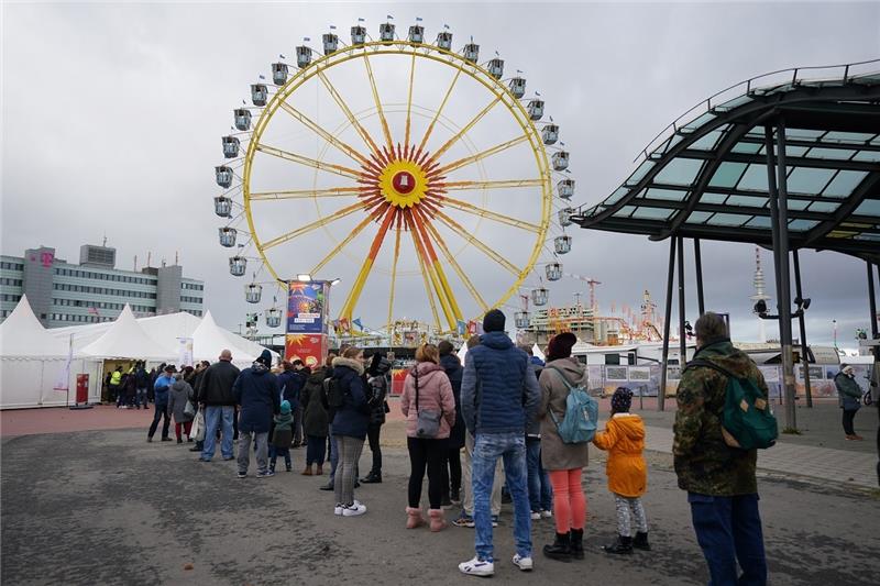 Besucher stehen vor dem Einlass für den Winterdom auf dem Heiligengeistfeld Schlange. Der Hamburger Winterdom hat unter 2G-Bedingungen begonnen. Foto: Marcus Brandt/dpa