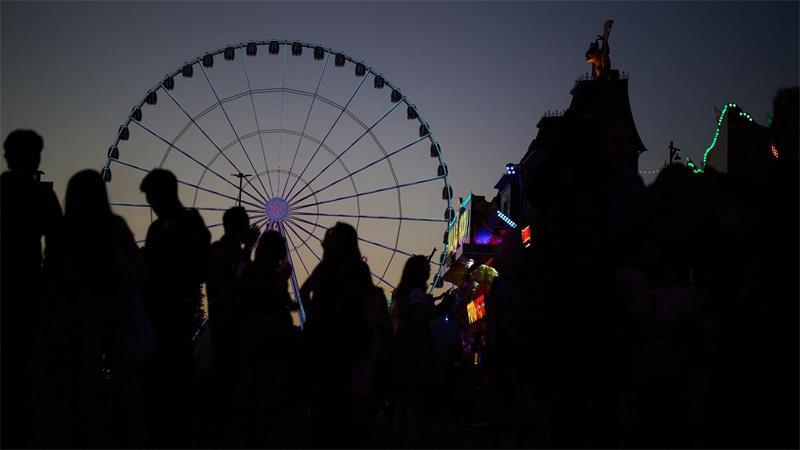 Besucher zeichnen sich vor einem Riesenrad auf dem Cannstatter Volksfest ab.