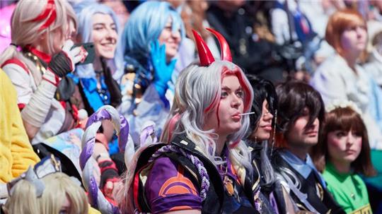 Besucherinnen und Besucher in Kostümen sitzen bei einem Weltrekordversuch auf der Gaming-Messe Polaris Convention im Auditorium.