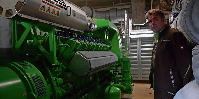 Biogas: Heizen mit Energie aus Mist und Mais Betreiber Tim Schröder vor dem Motor seiner Biogasanlage in Ebersdorf. Zusammen mit seinem Bruder Jörg betreibt er zwei Anlagen. Die Gemeinde deckt mehr als 50 Prozent ihresBedarfs an Strom und Wärme aus regional erzeugter Bioenergie. Damit zählt Ebersdorf zu den sogenannten Bioenergiedörfern. Foto: EPD