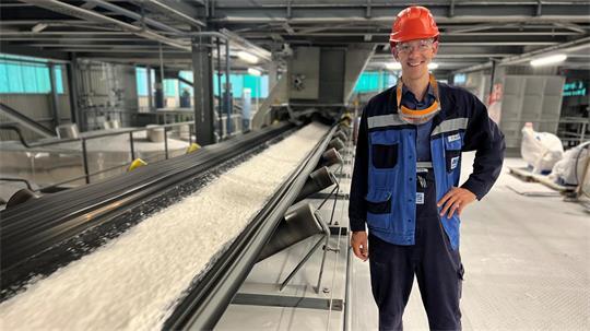 Betriebsleiter Felix Wolters steht an einem Förderband für das weiße Aluminiumoxid.