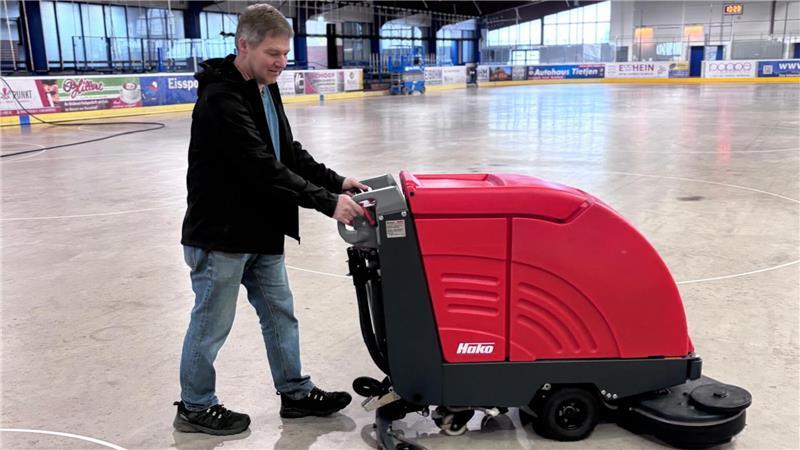 Betriebsleiter Michael Wege geht mit einer Scheuersaugmaschine über die Betonfläche.